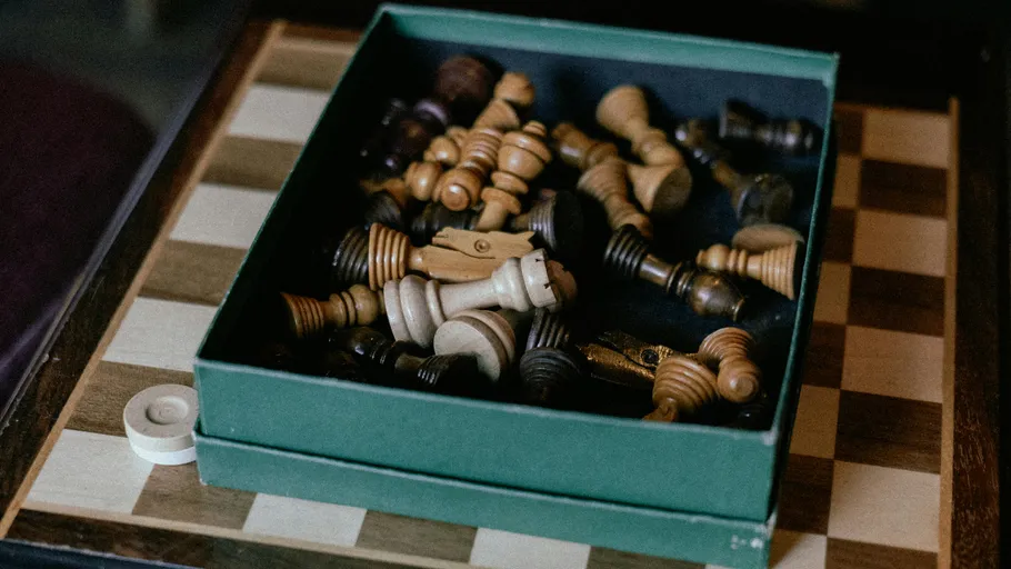 Box of chess pieces on chessboard.