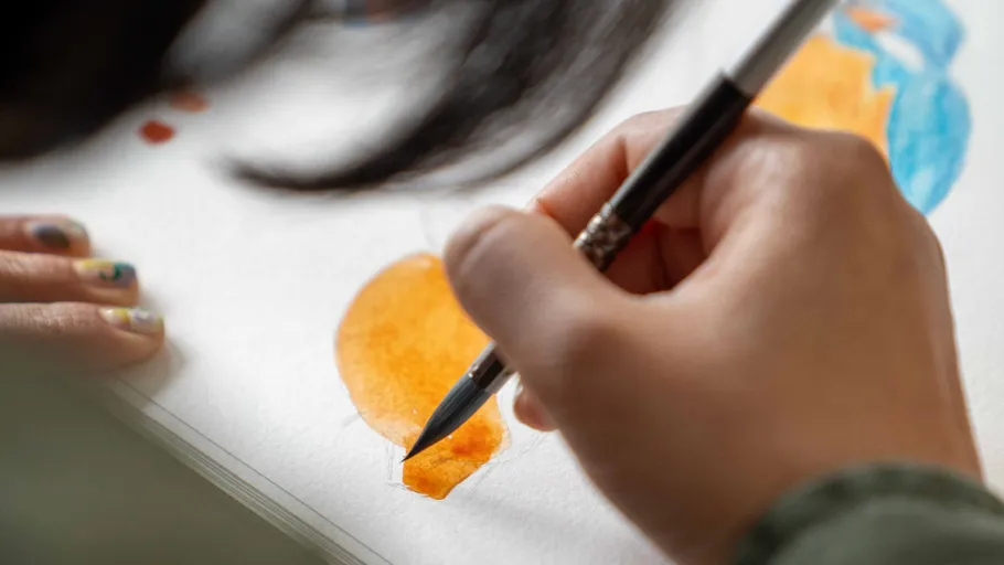 Hand malt mit Pinsel auf weißem Papier.