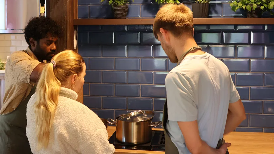 Drei Personen kochen zusammen in einer Küche.