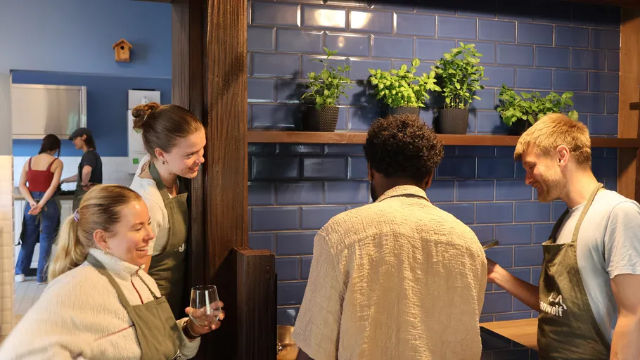Group of people chatting in kitchen with blue tiles.