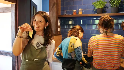 Woman holding food in kitchen with friends.