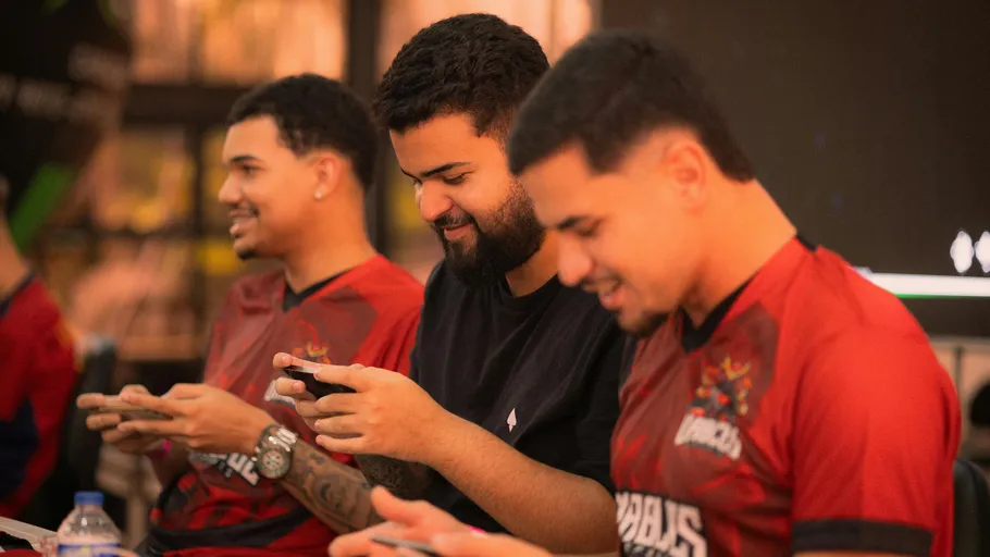 Three men sitting, focused on mobile games.
