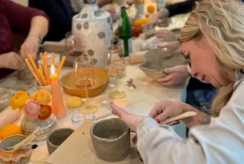 Woman crafting pottery in group setting.