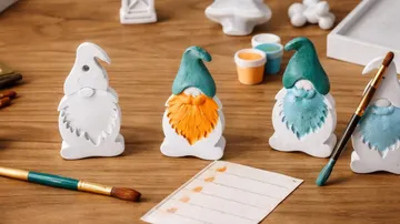 Painted gnomes on table, brushes and paints.