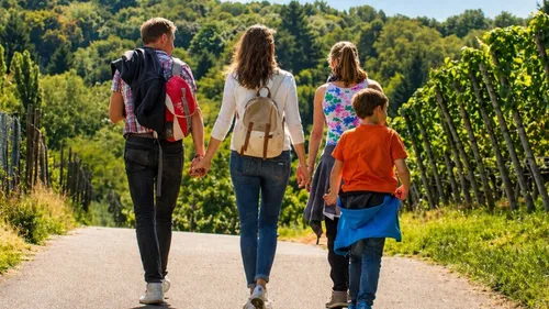 Familie spaziert Hand in Hand auf Weingutweg.