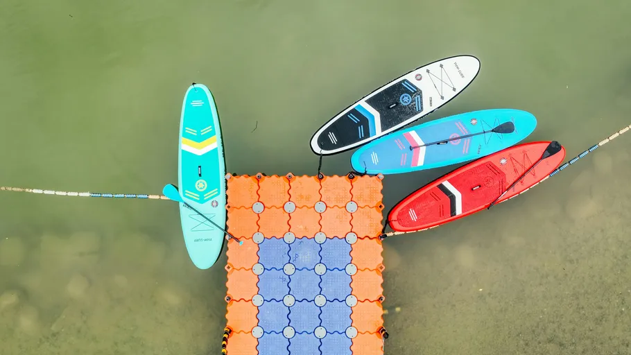 Four paddleboards tied to a floating dock.