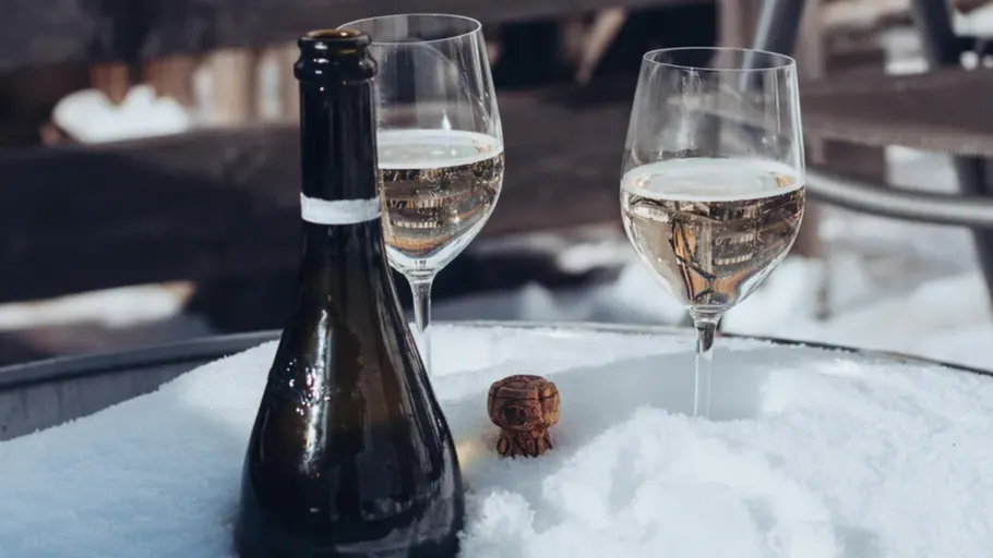 Two wine glasses and bottle in snow.
