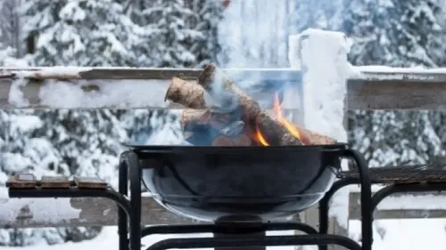 Feuer brennt im Grill vor Schneehintergrund.