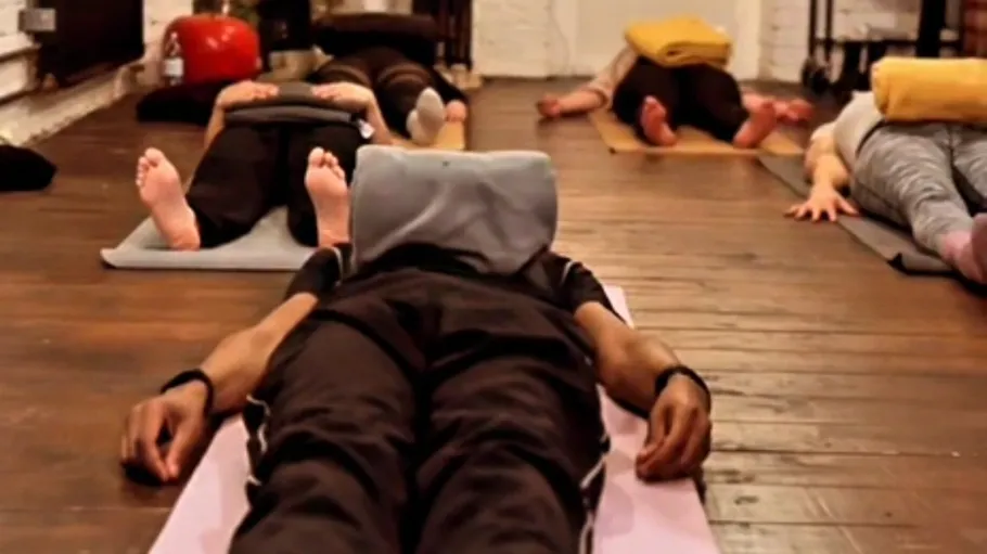 Personen liegen auf Matten mit Handtüchern im Yoga-Kurs.