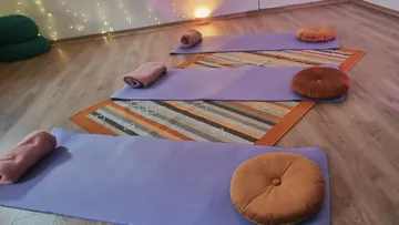 Yogamatten mit Kissen und gerollten Handtüchern.