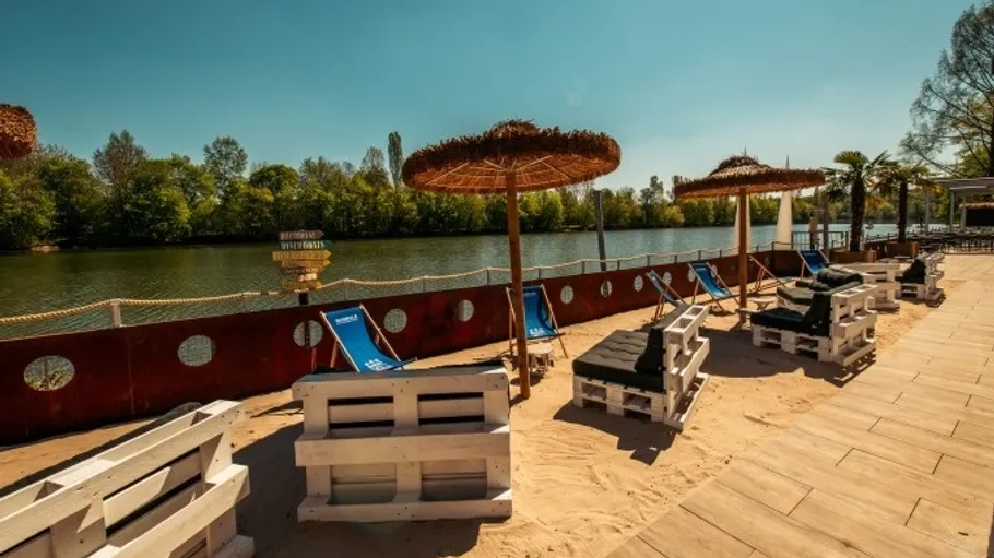 Liegestühle auf sandigem Flussuferstrand.