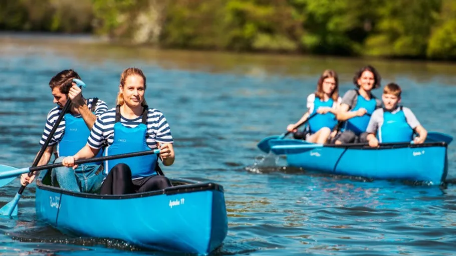 Zwei blaue Kanus paddeln auf einem Fluss.