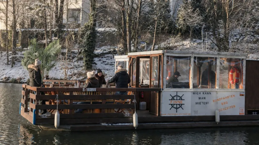 Gruppe auf schwimmendem Boot im verschneiten Kanal.