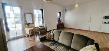 Wohnzimmer mit Sofa und großen Fenstern.