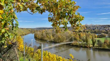 Hängebrücke über Fluss, Herbstlandschaft.