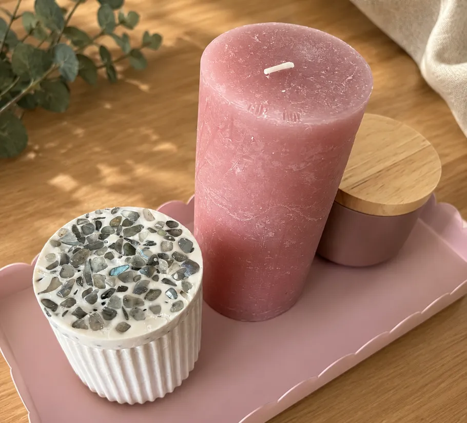 Pink candle and decorative boxes on tray.