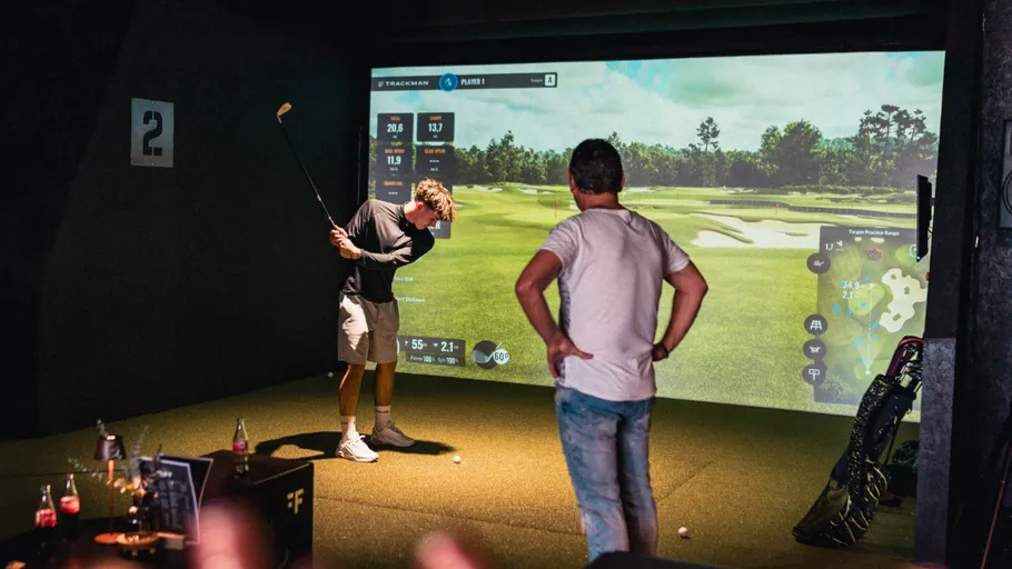 Zwei Männer spielen Indoor-Golfsimulation.