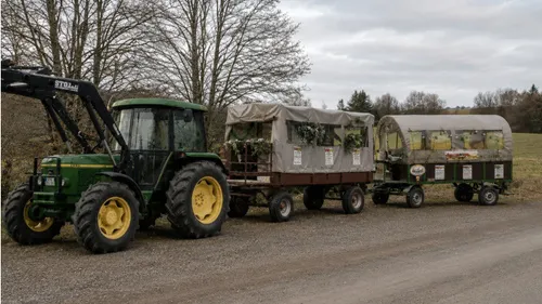 Tractor towing two covered wagons on road.