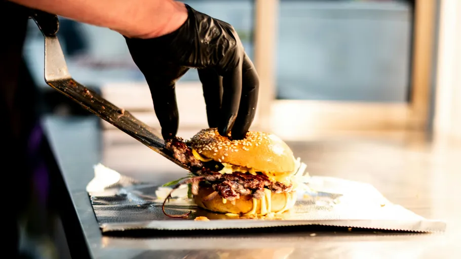 Koch mit Handschuh bereitet Gourmet-Burger zu.