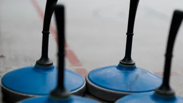 Blaue Eisstock-Steine auf Eisfläche.