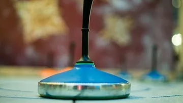Nahaufnahme eines Curlingsteins auf Eis.
