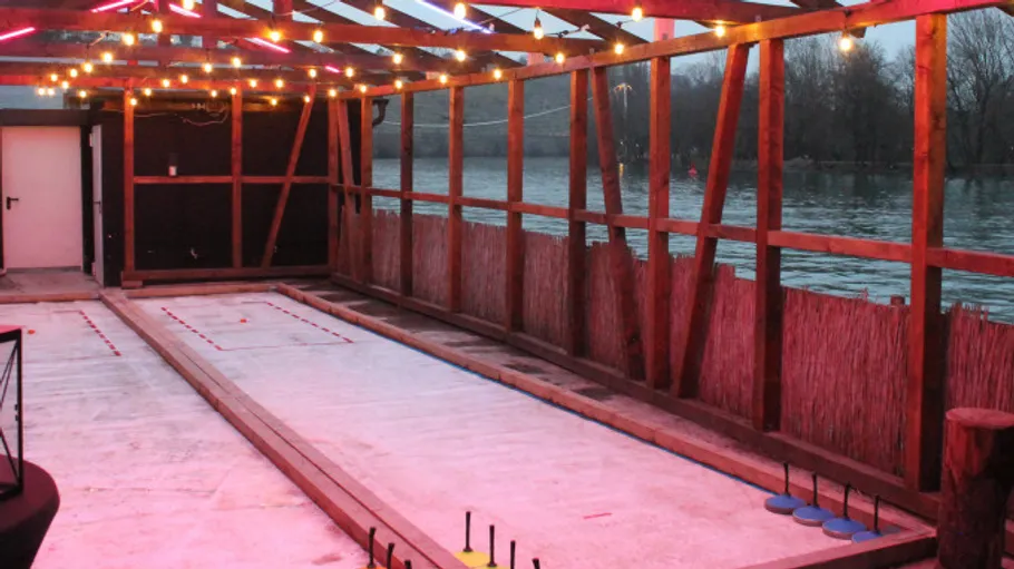 Outdoor ice curling rink with string lights.