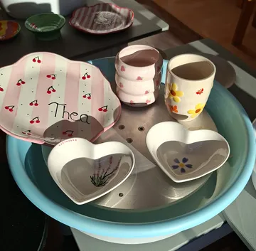 Ceramics with floral and cherry designs in sunlight.