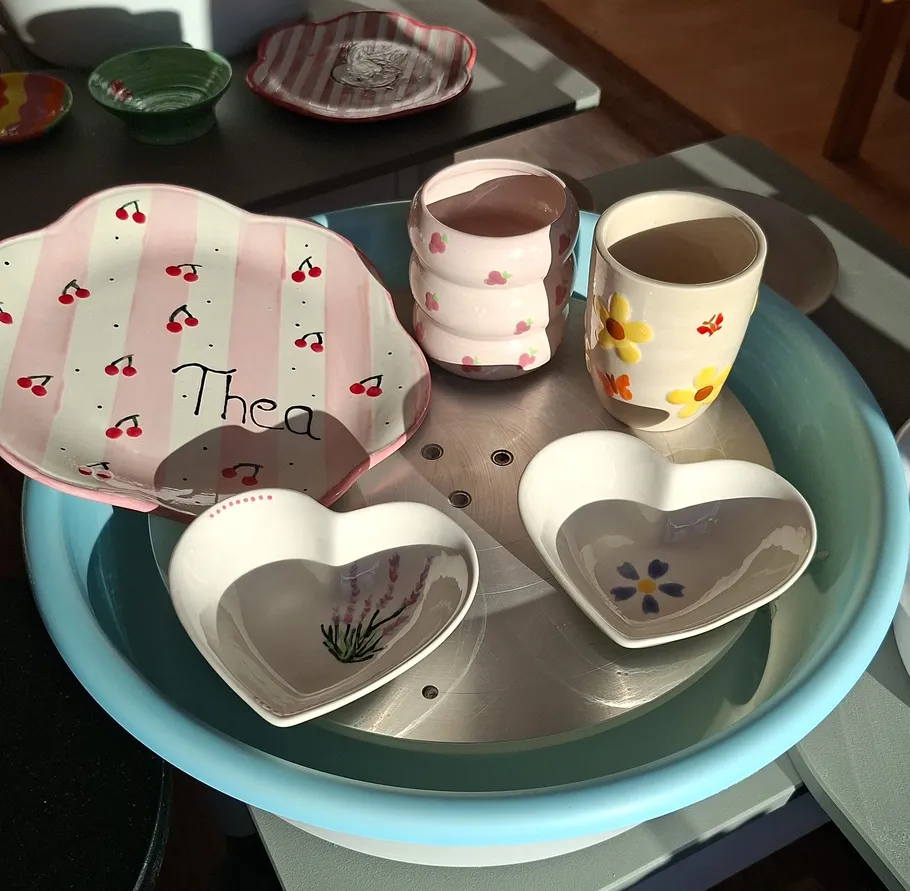 Ceramics with floral and cherry designs in sunlight.