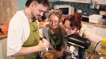 Three people baking together in kitchen.