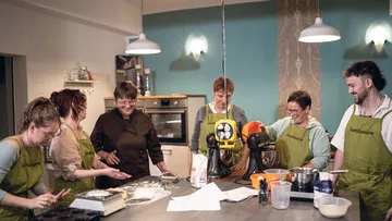 Group baking in modern kitchen with mixers.