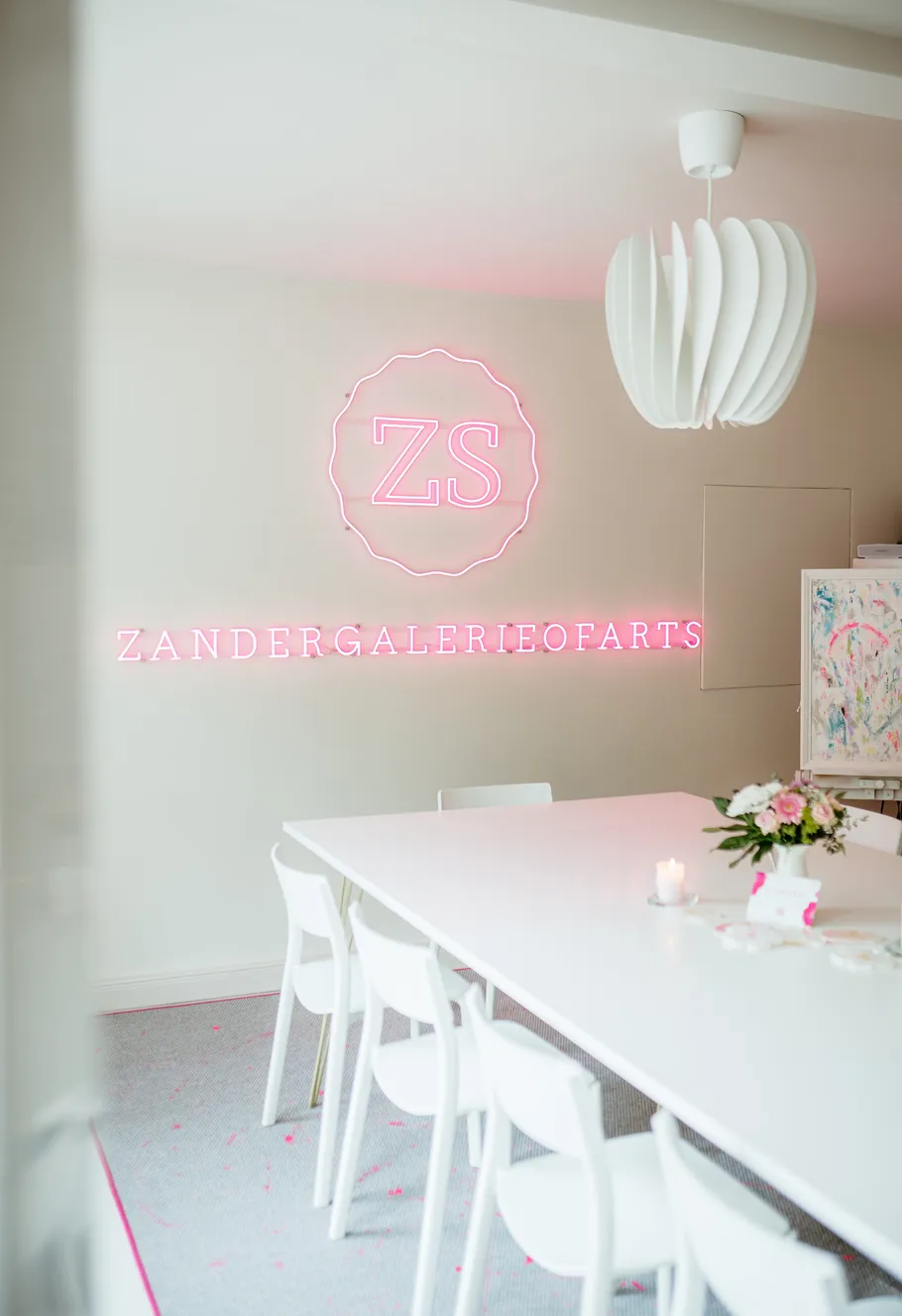 Moderner Raum mit Neonschild und weißen Möbeln.