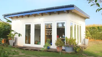 Small white garden house with glass doors.