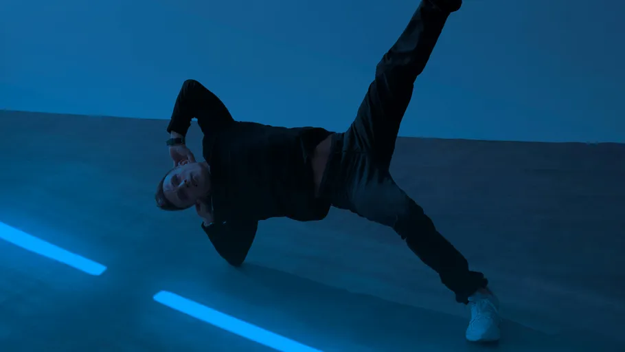 Person doing side plank in blue-lit room.