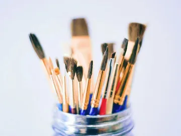 Brushes stand upright in a glass container.