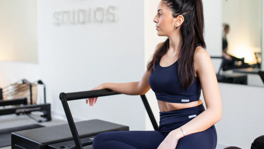 Woman sitting on Pilates reformer in studio.