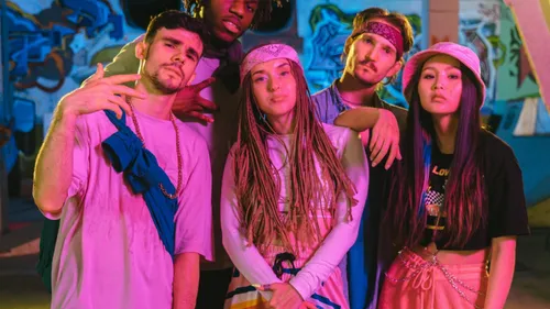 Five people posing in urban graffiti setting.