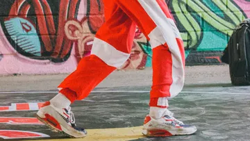 Person in rotem Trainingsanzug neben Graffiti-Wand.