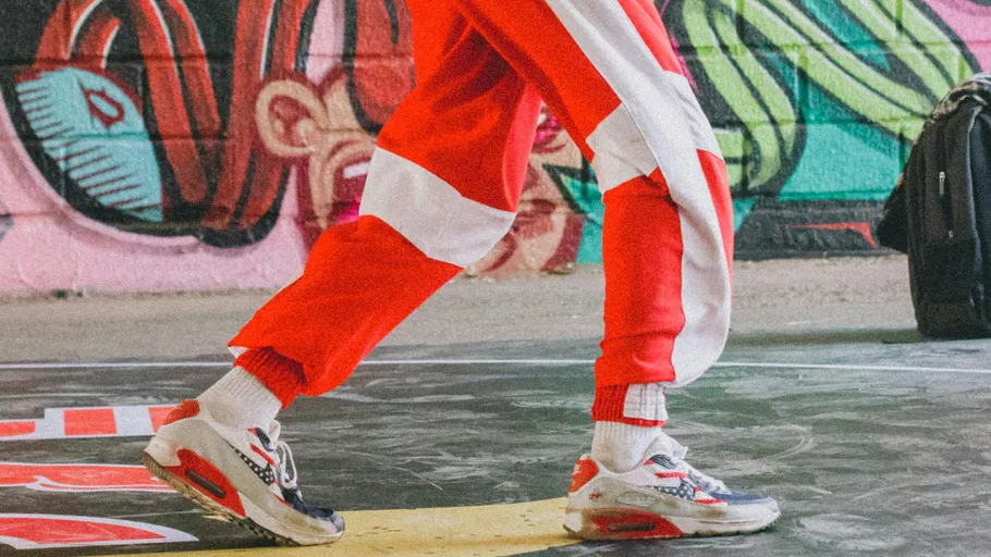 Person in rotem Trainingsanzug neben Graffiti-Wand.
