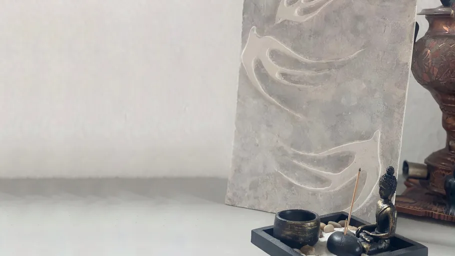 Buddha statue with incense and artwork on table.