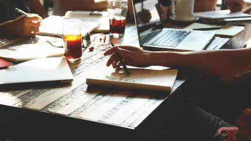 Menschen schreiben an einem Tisch mit Laptops.