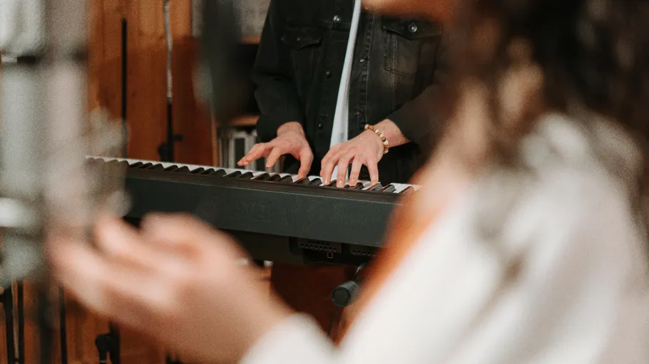 Person spielt Keyboard, verschwommene Hand im Vordergrund.