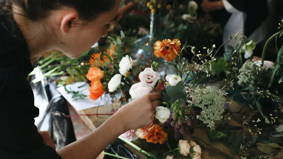 Person arrangiert Blumen auf einem Tisch.