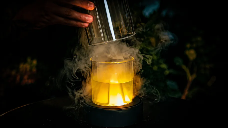 Glas mit rauchigem Getränk unter Glasabdeckung.