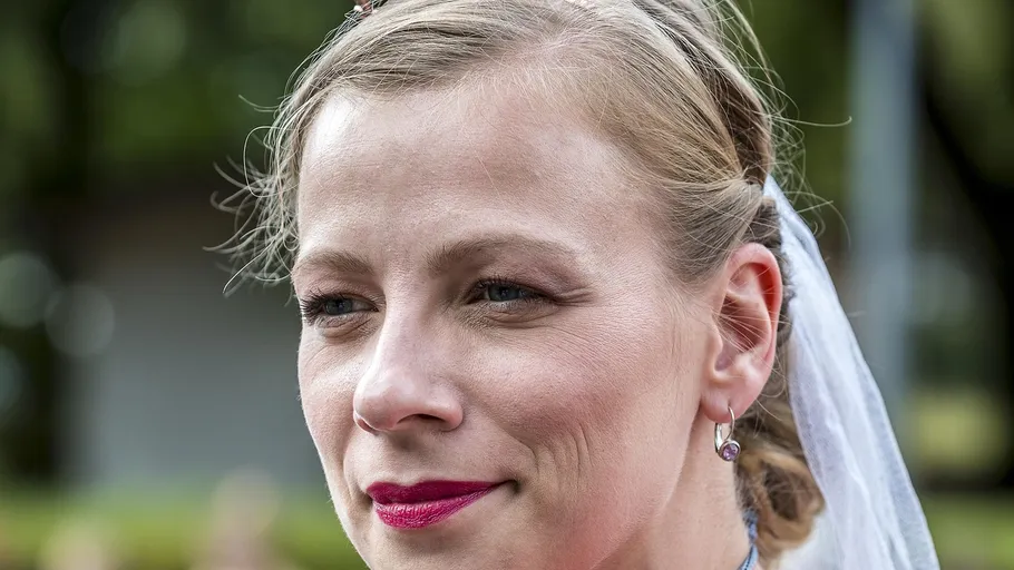Frau lächelt draußen mit Schleier und Ohrringen.