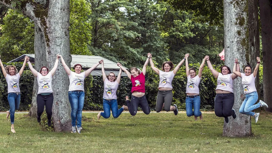 Group of women jumping in park holding hands.