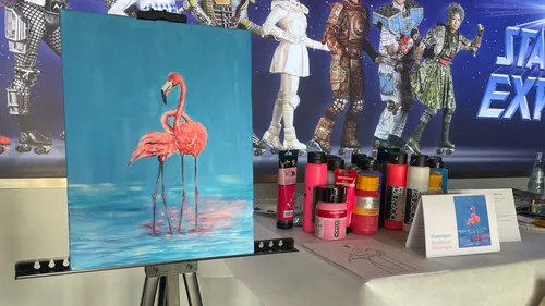 Flamingo painting with paint bottles, roller skate backdrop.
