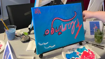 Leinwand mit buntem Text auf Staffelei, Hand berührt.