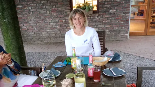 Frau sitzt draußen an einem Tisch mit Getränken.