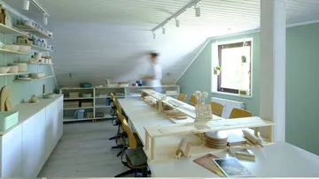 Workspace with long table and shelves, person blurred.