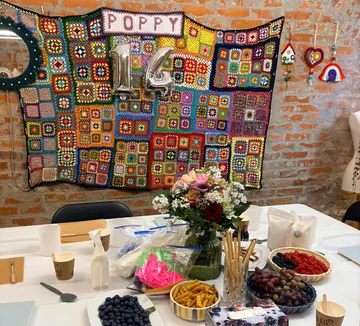 Bunte Häkeldecke mit Geburtstagsdekorationen an der Wand.